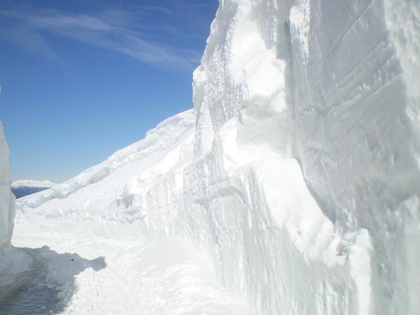 La strada chiusa al traffico tra due alte pareti di neve