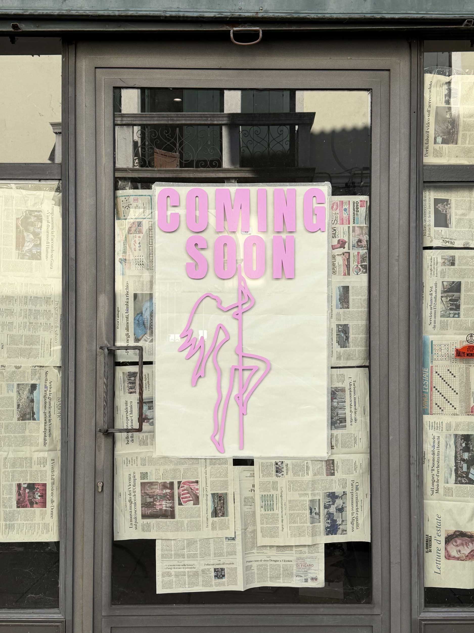 Curiosità e attesa in centro a Bassano: vetrina coperta di giornali con la scritta "Coming Soon"